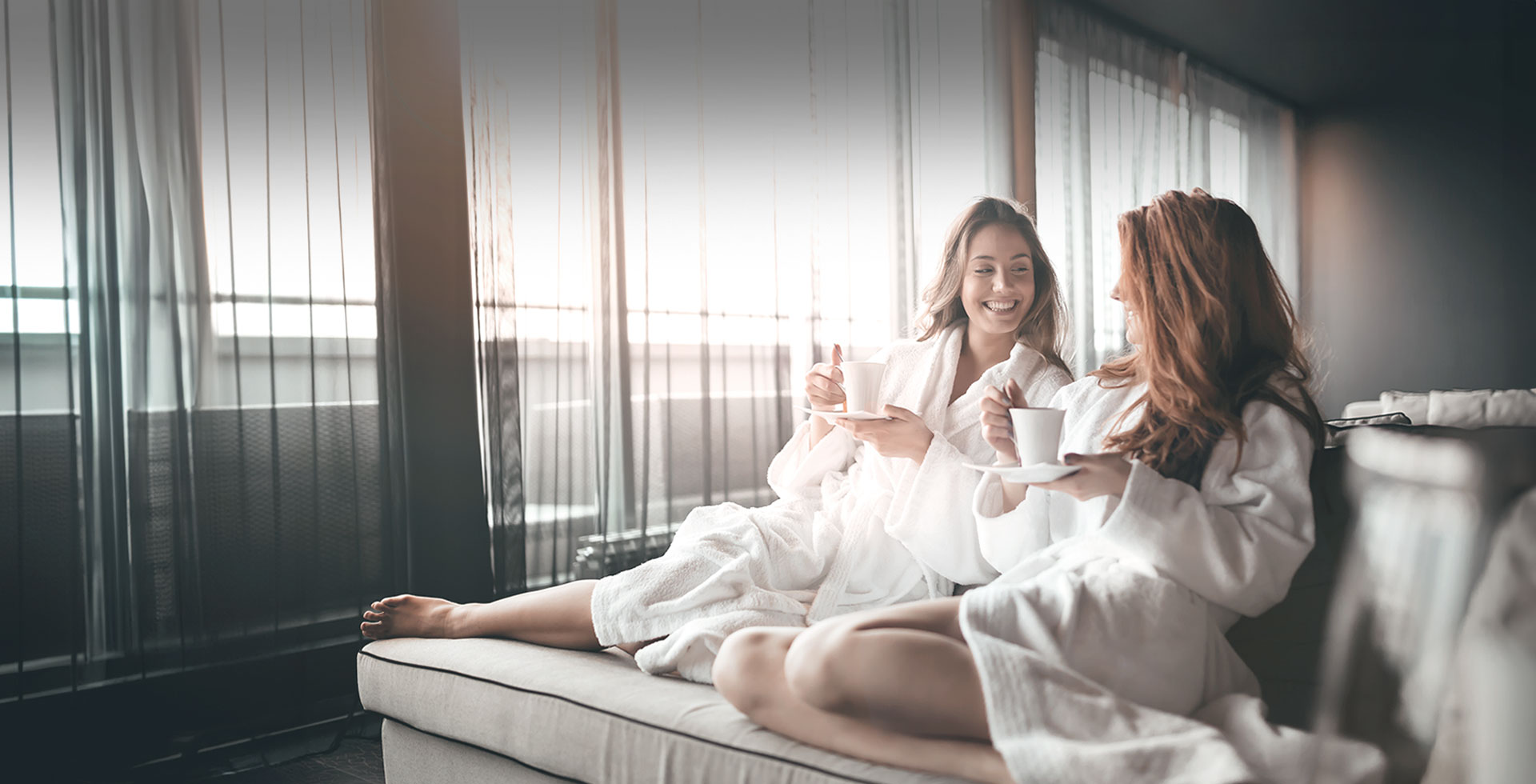 Book an unforgettable friends trip with your best friend at TRIFORÊT alpin.resort. Two friends in bathrobes enjoy coffee in the stylish hotel room of the TRIFORÊT alpin.resort.
