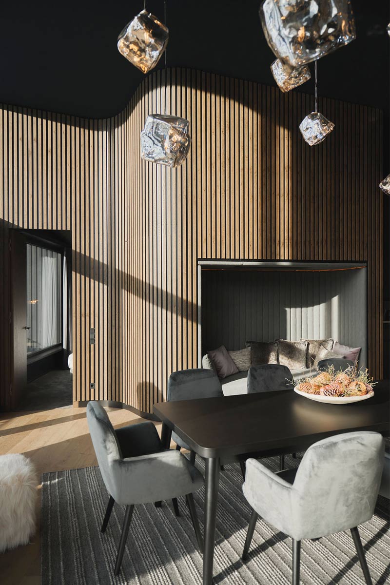 A place for moments of pleasure during your ski vacation in Hinterstoder. Bright dining area with designer chairs, wood paneling and cozy seating area in the chalet at TRIFORÊT alpin.resort.